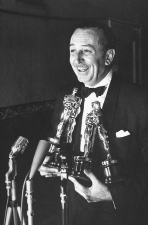 Walt Disney sonríe mientras sostiene sus cuatro premios Oscar por dos largometrajes animados y dos documentales, en 1954.