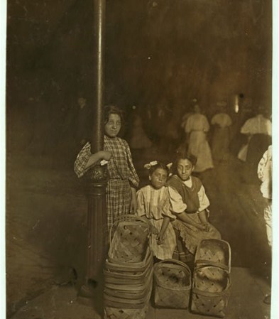 Niños vendiendo canastas artesanales durante la noche.