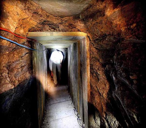 OTAY MESA, CA - NOVEMBER 30: An investigator combs through a drug tunnel found in a wherehouse on November 30, 2011 in Otay Mesa, California. The tunnel, which led from the United States to a small business building in Tijuana, was the most sophisticated tunnel ever found in California and included an elevator, wood flooring an lighting. (Photo by Sandy huffaker/Getty Images)