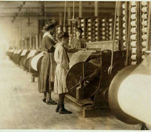 Una mujer enseña a una niña las labores dentro de una fábrica textil
