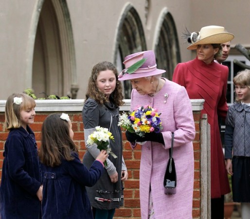 La Reina Isabel recibió las flores que unas niñas le regalaron.