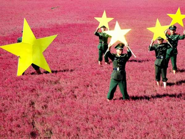 Soldados chinos sostienen las estrellas parte de la bandera de su país, al recrear la enseña nacional en una playa floreada.