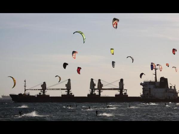 Surfistas en cometas vuelan sobre un carguero en el área de aproximación al puerto de Ciudad del Cabo.