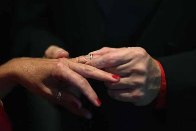 WEST PALM BEACH, FL - FEBRUARY 14: Douglas Brown slips a ring on the finger of his wife, Karen Brown as they are wed during a group Valentine's day wedding at the National Croquet Center on February 14, 2013 in West Palm Beach, Florida. The group wedding ceremony is put on by the Palm Beach Country Clerk & Comptroller's office and approximately 40 couples tied the knot. (Photo by Joe Raedle/Getty Images)