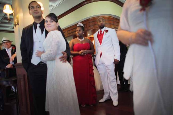 WEST PALM BEACH, FL - FEBRUARY 14: Rovetta Jones and David Jones (C) stand together as they wait to be wed during a group Valentine's day wedding at the National Croquet Center on February 14, 2013 in West Palm Beach, Florida. The group wedding ceremony is put on by the Palm Beach Country Clerk & Comptroller's office and approximately 40 couples tied the knot. (Photo by Joe Raedle/Getty Images)
