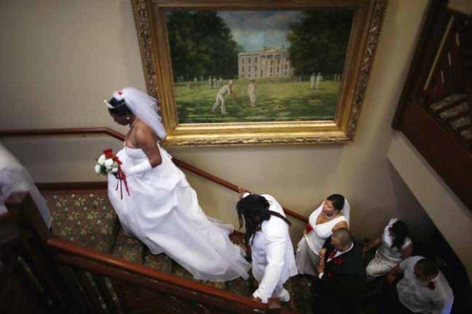 WEST PALM BEACH, FL - FEBRUARY 14: Brides and their grooms walk up the stairs to be wed as they participate in a group Valentine's day wedding at the National Croquet Center on February 14, 2013 in West Palm Beach, Florida. The group wedding ceremony is put on by the Palm Beach Country Clerk & Comptroller's office and approximately 40 couples tied the knot. (Photo by Joe Raedle/Getty Images)