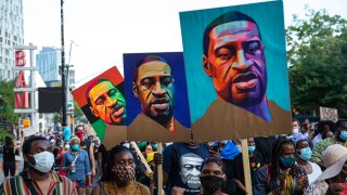 Pedestrians carry posters depicting George Floyd during a Juneteenth protest march on June 19, 2020, in the Brooklyn borough of New York City.