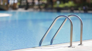 Una piscina sin bañistas permanece con el agua en calma.