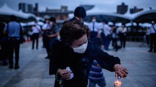 A visitor burns incense to pay tribute to the atomic bomb victims in front of the cenotaph at the Hiroshima Peace Memorial Park in Hiroshima on August 6, 2020 to mark 75 years since the world's first atomic bomb attack.