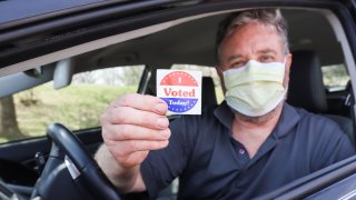 Hombre con mascarilla vota desde su auto
