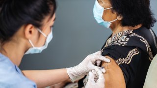 Una enfermera colocando la vacuna a una señora