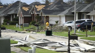 A person picks up debris damage near their home in Laplace, Louisiana, on August 30, 2021 after Hurricane Ida made landfall.