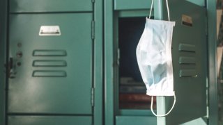 COVID mask hanging inside school on locker.