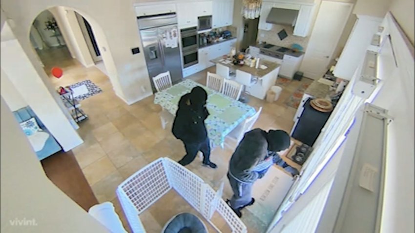 Two people dress in dark clothes in a kitchen