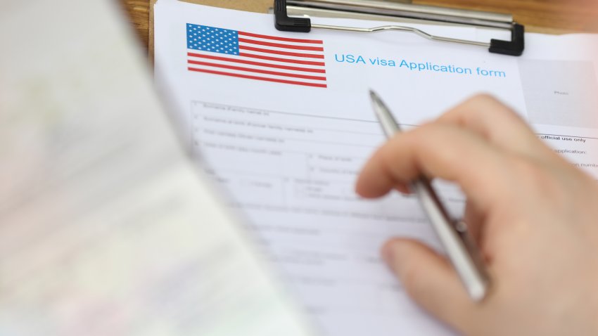 Close-up of clipboard with usa visa application form on first page. Persons hand with pen to fill spaces. Journey to another country and exploring concept