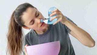 Irrigación nasal. Una persona usa el Neti Pot para tratar la secreción nasal y los resfriados.