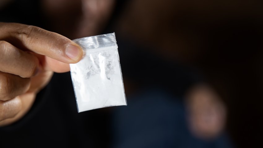 Man hand holds plastic packet or bag with cocaine or another drugs, drug abuse and danger addiction concept.