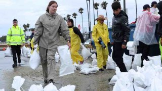 Voluntarios y miembros del Departamento de Bomberos de Long Beach llenan sacos de arena en Belmont Shore Beach el 20 de agosto de 2023 en Long Beach, California.