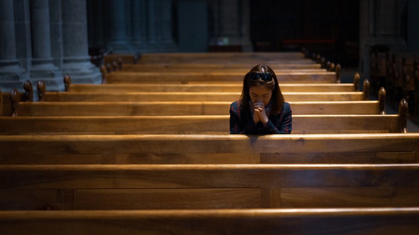 A Christian girl is sitting and praying with humble heart in the church.