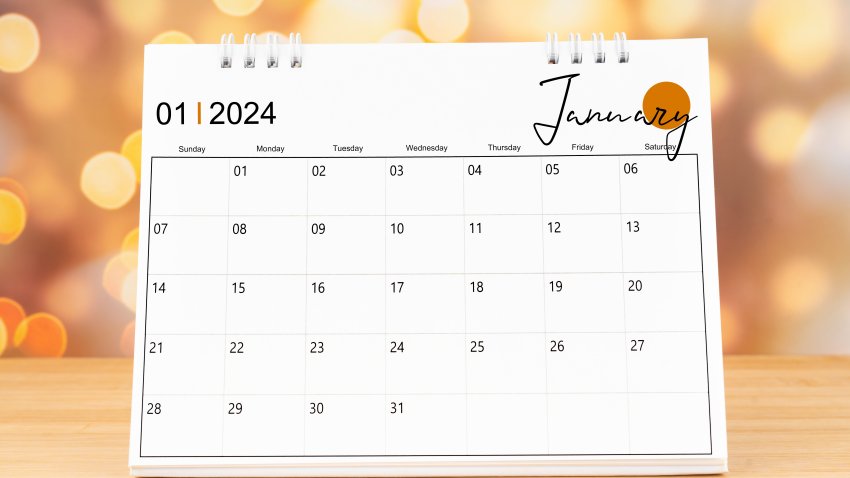 January 2024 desk calendar on wooden table with gold light bokeh background. New Year Concept.