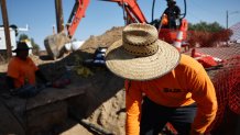 Oscar Rodríguez, José Delgado y Jesús Rodríguez trabajan en el calor de la tarde durante una ola de calor de larga duración que continúa impactando gran parte de California el 10 de julio de 2024 en Baker, California.