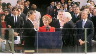 El presidente electo Ronald Reagan presta juramento durante las ceremonias de inauguración en Washington, DC. Su esposa, Nancy, sostiene la Biblia y el presidente del Tribunal Supremo, Warren Burger, le toma juramento.