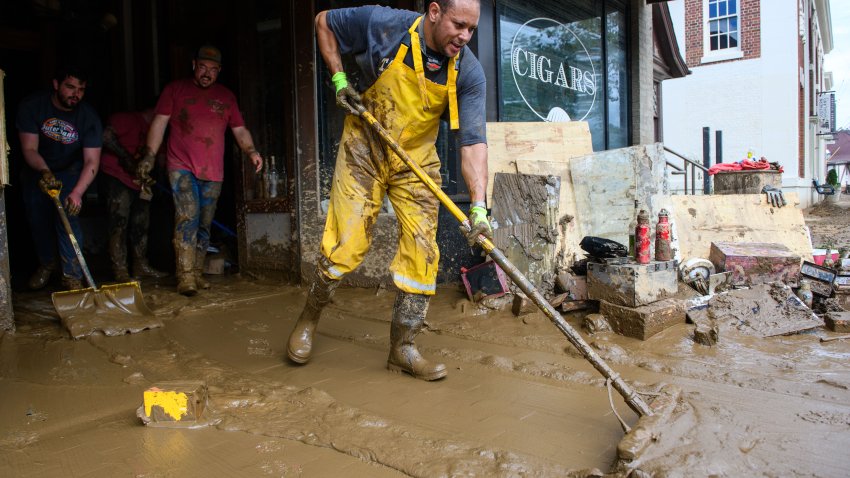 ASHEVILLE, CAROLINA DEL NORTE – 01 DE OCTUBRE: Sam Souhail, a la derecha, propietario del Casablanca Cigar Bar, limpia el barro de su tienda en el Biltmore Village frente al Biltmore Estate tras el paso del huracán Helene el 1 de octubre de 2024 en Asheville, Carolina del Norte.