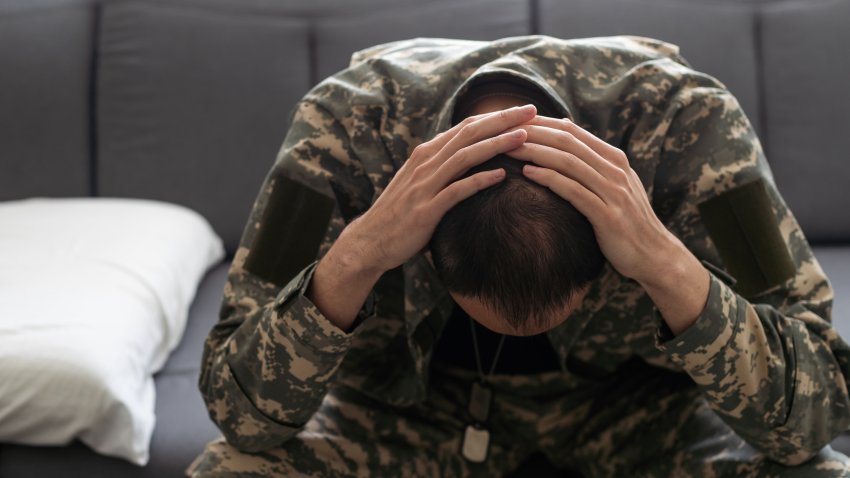 Having flashbacks. Post traumatic stress disorder. Soldier in uniform sitting indoors. High quality photo