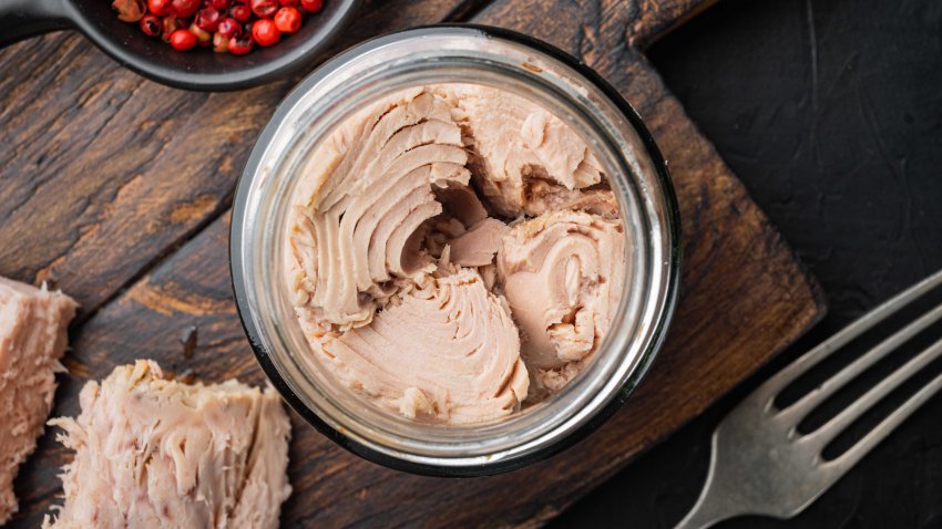 Canned tuna fillet meat in olive oil, on black background, flat lay