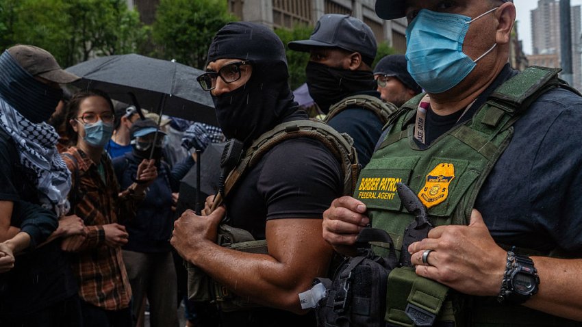 A line of ICE and Border Patrol agents in tactical gear face off with protestors holding umbrellas during a rainy standoff in New York USA on June 7 2025. (Photo by Madison Swart / Hans Lucas via AFP) (Photo by MADISON SWART/Hans Lucas/AFP via Getty Images)