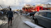 TOPSHOT – A man walks past a car and damaged buildings October 29, 2025 following the passage the previous day of Hurricane Melissa, in Black River, St. Elizabeth, Jamaica. Hurricane Melissa bore down on the Bahamas October 29 after cutting a path of destruction through the Caribbean, leaving 30 people dead or missing in Haiti and parts of Jamaica and Cuba in ruins. Somewhat weakened but still threatening, Melissa will bring damaging winds and flooding rains to the Bahamas Wednesday before moving on to Bermuda late Thursday, according to the US National Hurricane Center (NHC). (Photo by Ricardo Makyn / AFP) (Photo by RICARDO MAKYN/AFP via Getty Images)