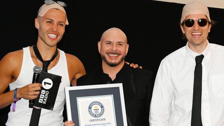 LONDON, ENGLAND – JULY 10: Pitbull (C) is presented with the Guinness World Record title for the ‘largest gathering of people wearing bald caps’ alongside BBC Radio 1 presenters Dean McCullough (L) and Greg James during BST Hyde Park 2026 at Hyde Park on July 10, 2026 in London, England. (Photo by Matthew Baker/Getty Images)